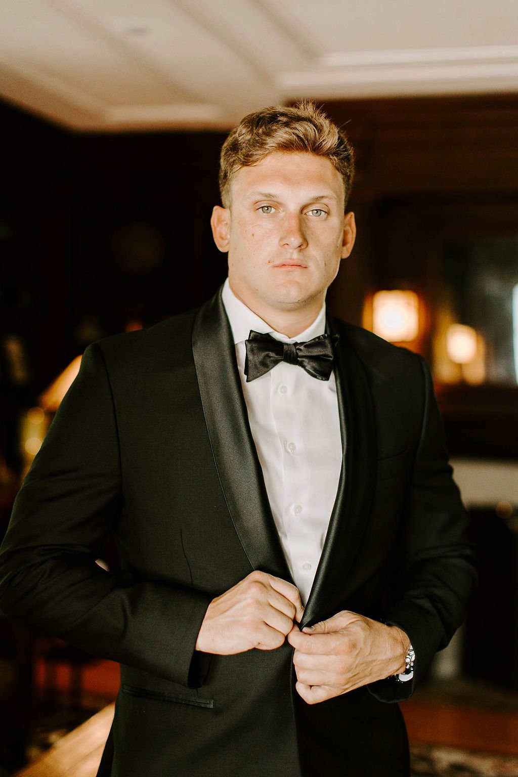 Groom posing in black suite and bow tie