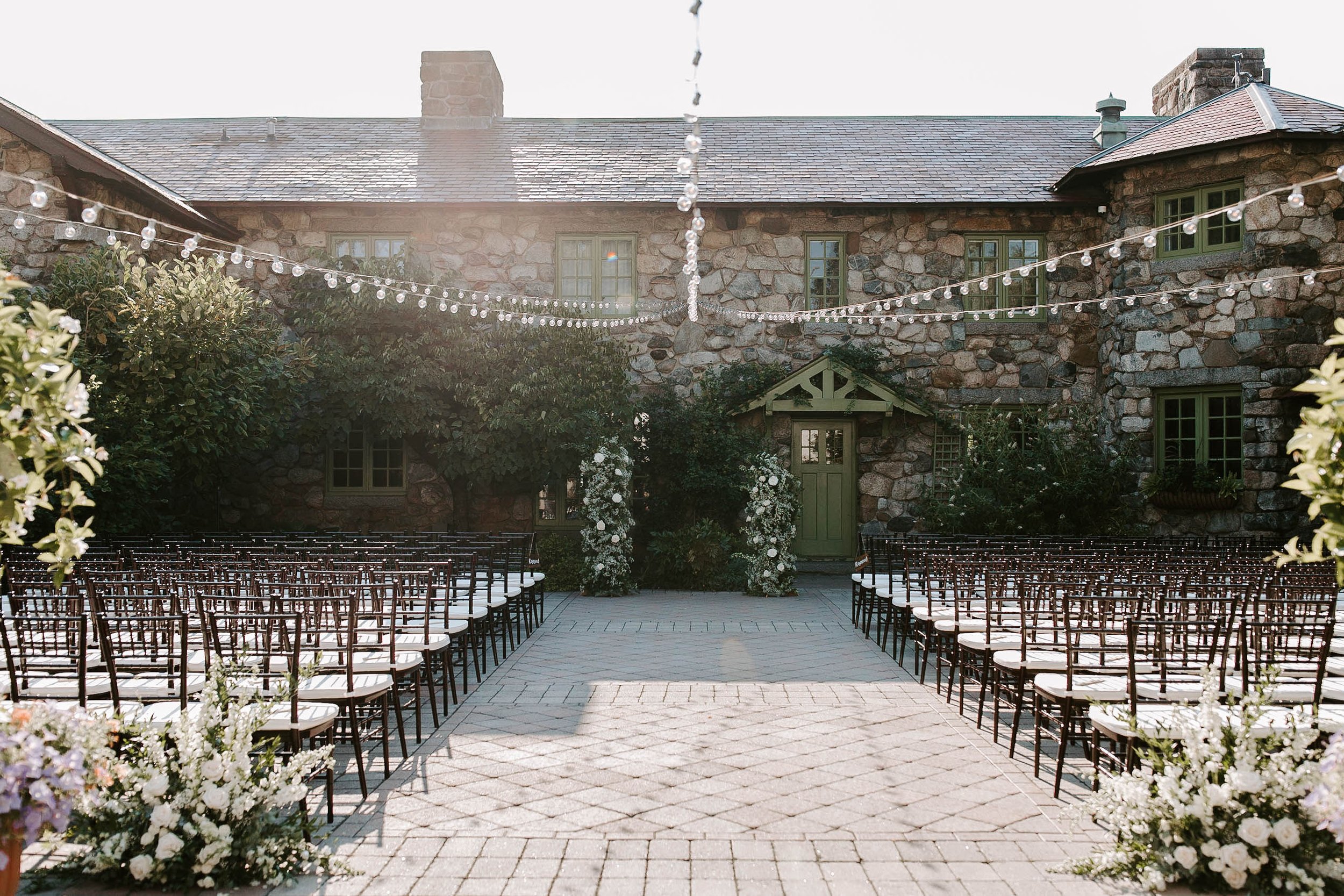 Ceremony setup, wooden seats and white and green floral arrangements