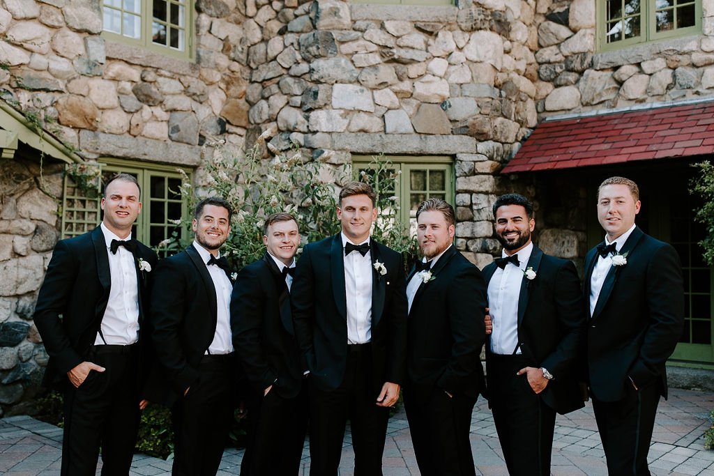 Groomsmen and Groom smiling posing in front of Willowdale Estate