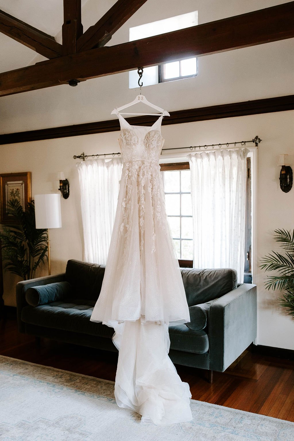 Lace wedding dress hanging from wooden beam