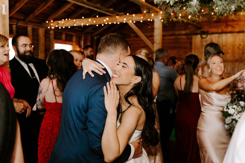 Bride hugging groom and smiling on the wedding reception dance floor