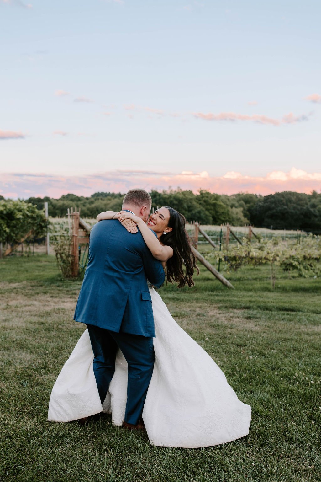 Bride and groom hugging and laughing in vineyards during sunset