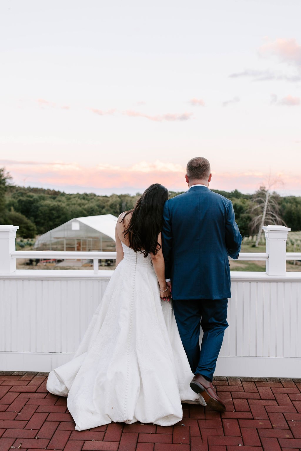 Bride and groom looking off into the distance on barn balcony during sunset