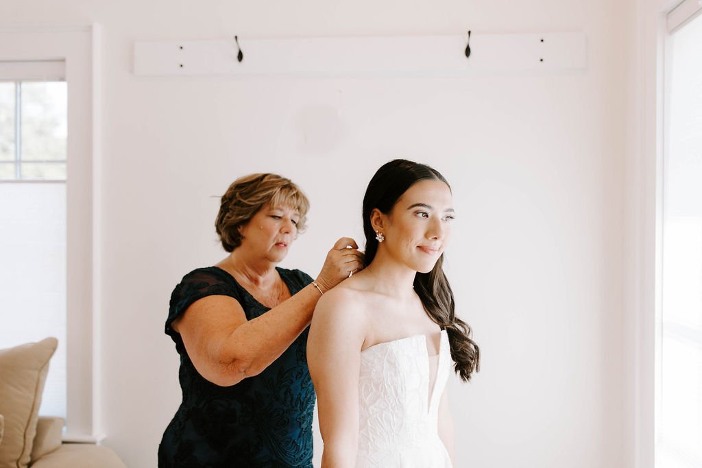 Mom of the bride helping bride get ready on her wedding day