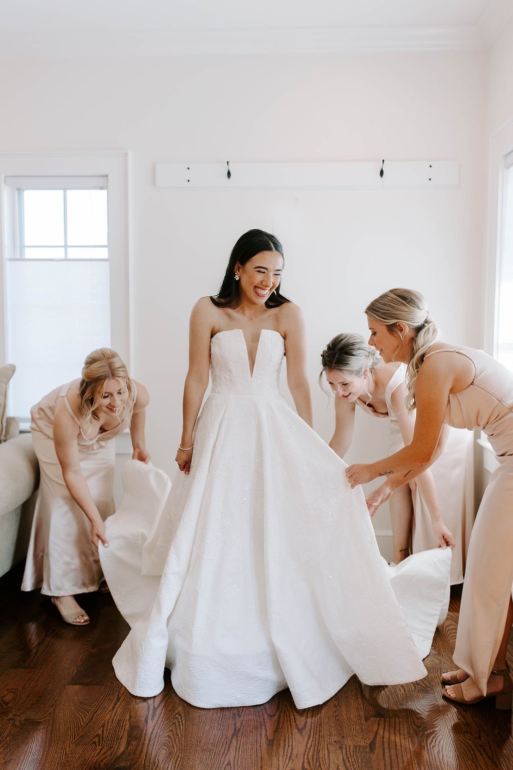 Bride smiling while her bridesmaids help her get ready for her barn wedding