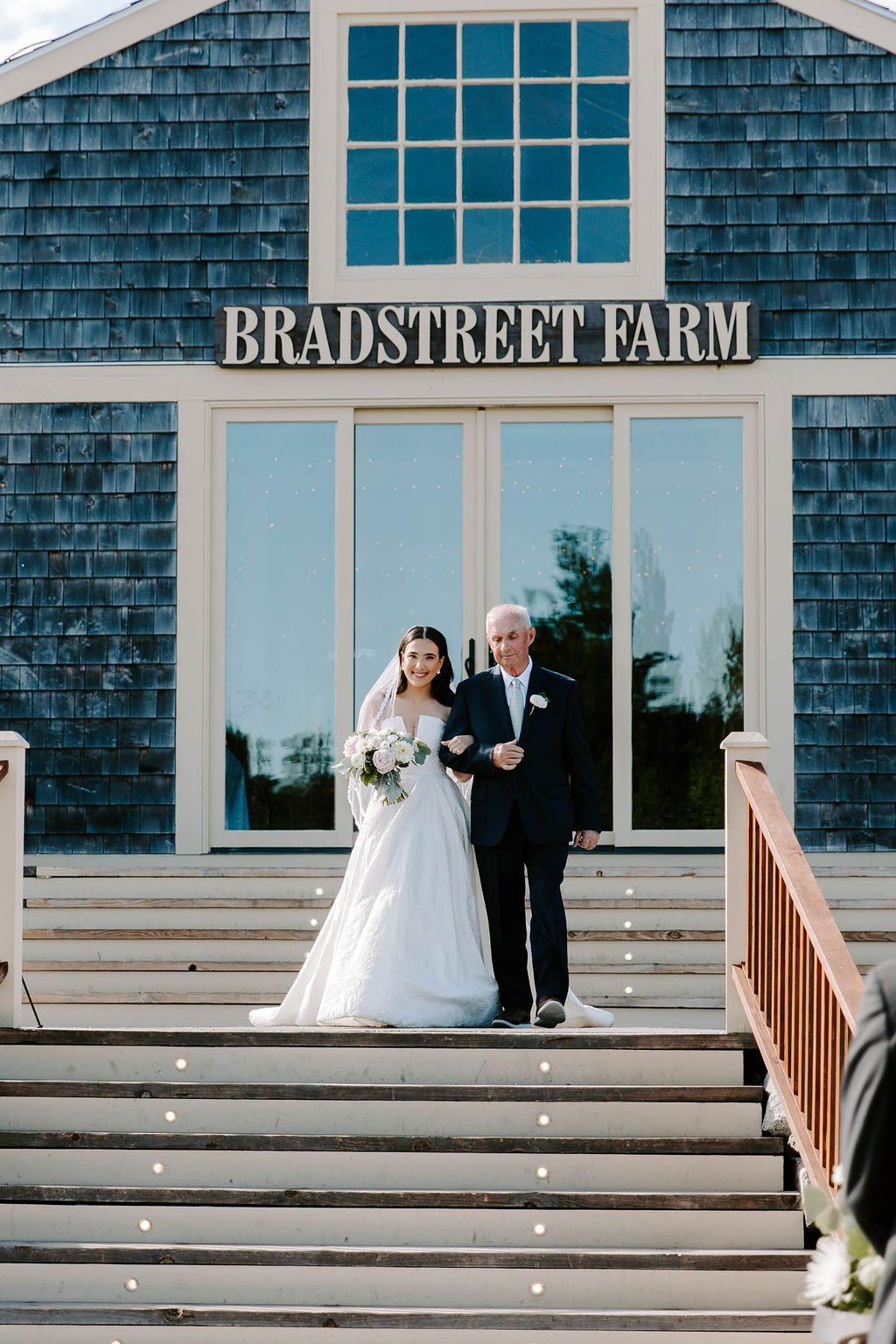 Bride walking down steps with father towards wedding aisle 