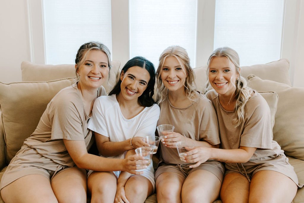 Bride and bridesmaids smiling and toasting glasses