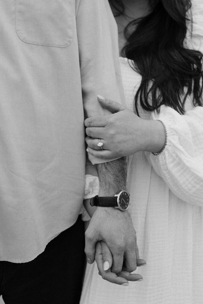 Man holds woman's arm during Wingaersheek Beach engagement shoot