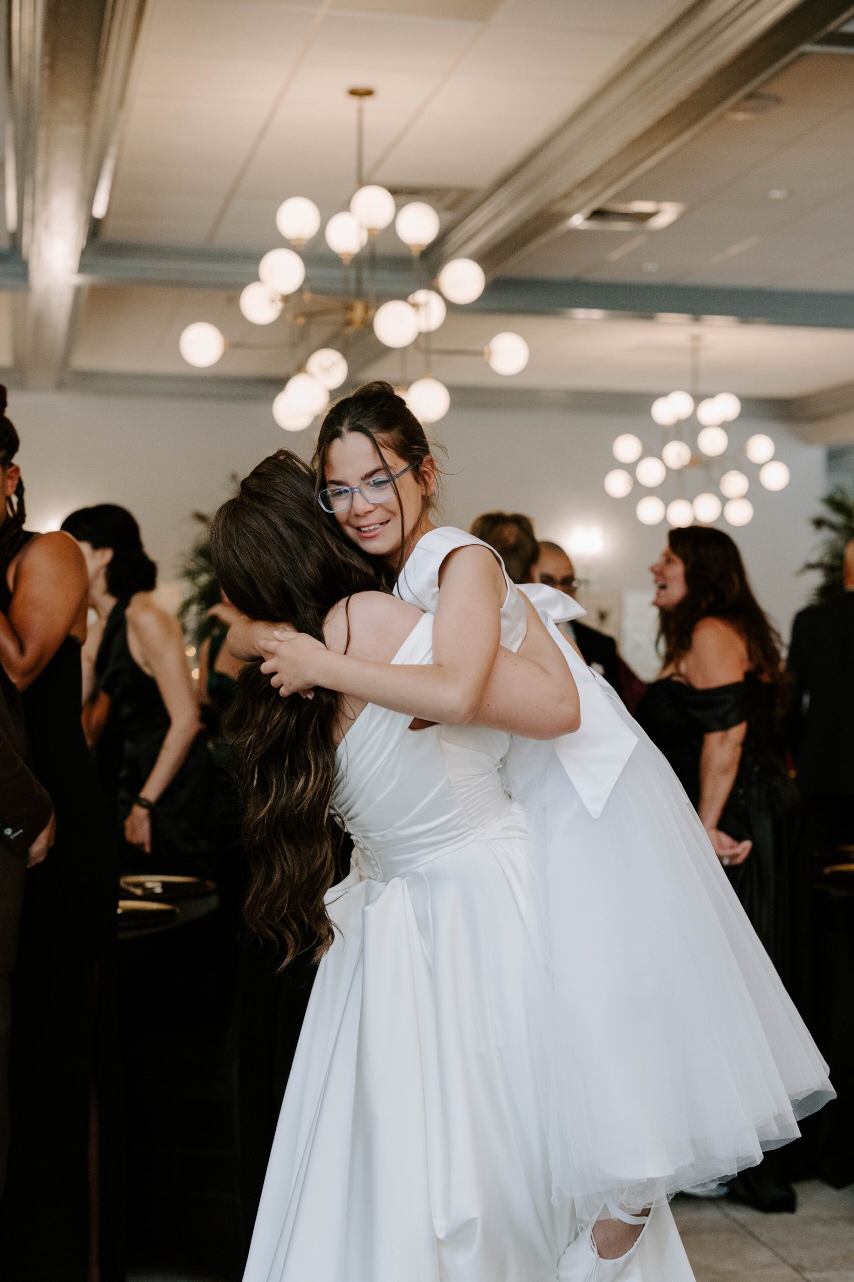 Bride and flower girl hug at wedding reception