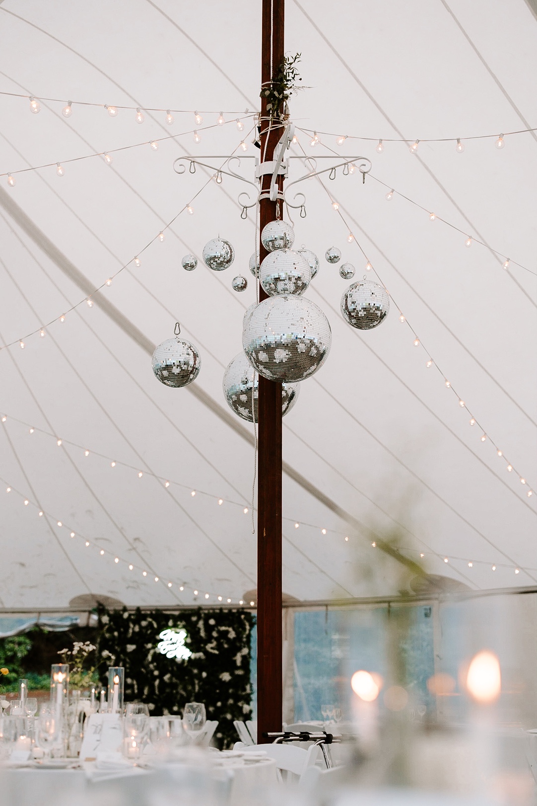 Disco balls hanging from the top of the wedding reception tent