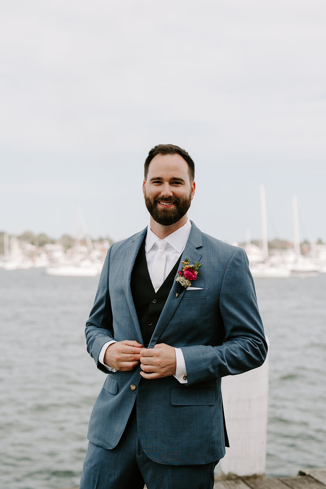 Handsome groom poses with the sea in the background