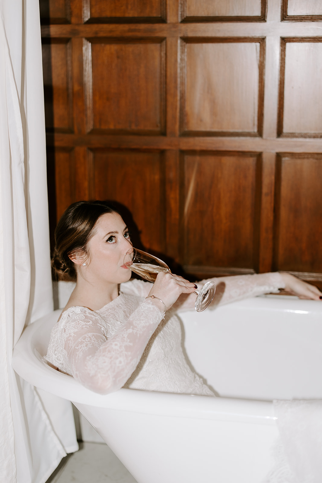 Bride poses in the bathtub with a glass of wine on her dreamy Stevens estate wedding day