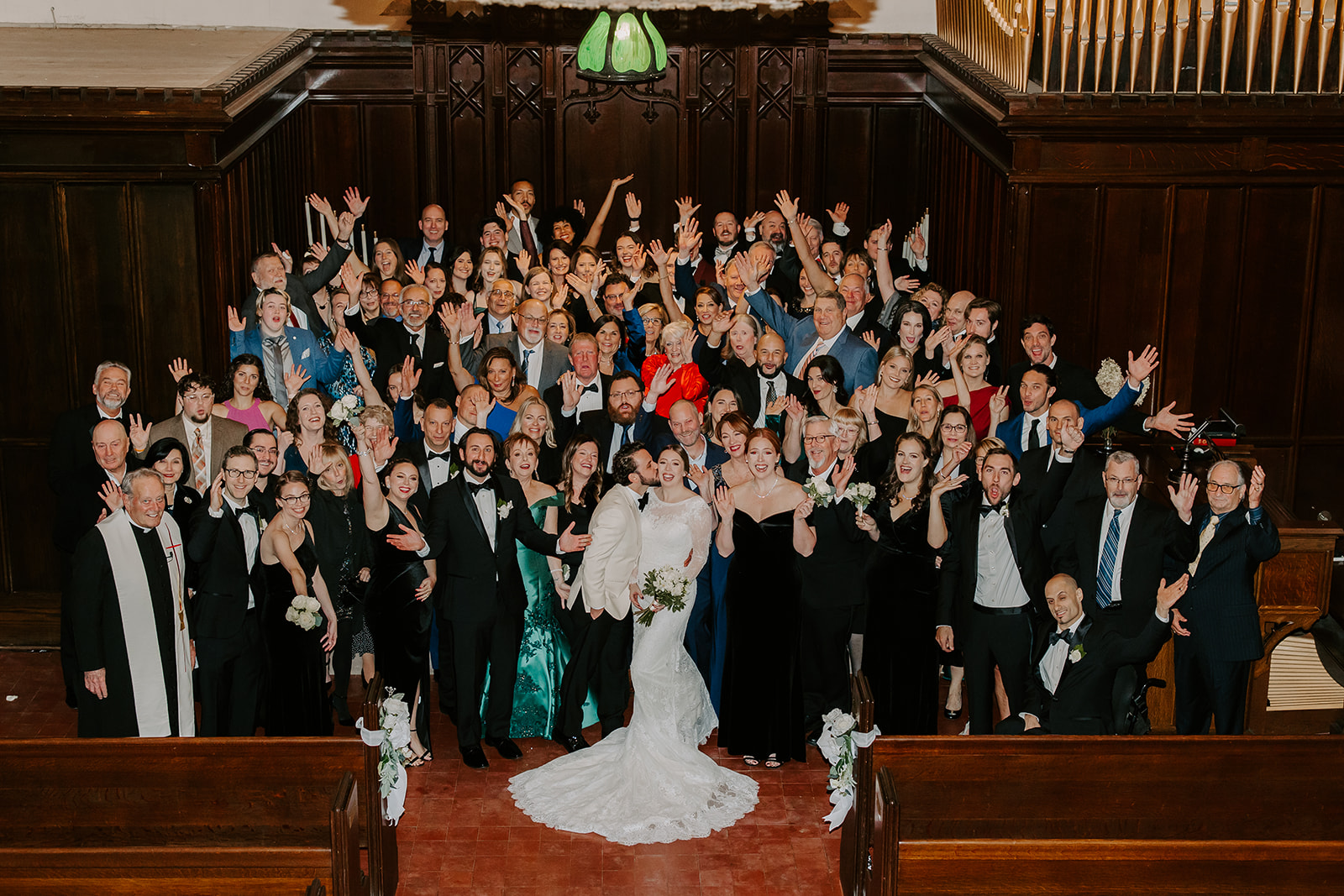 Bride and groom pose together surrounded by their guests