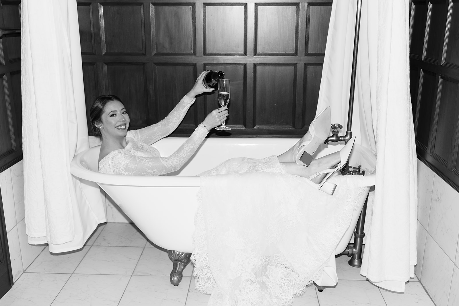 Bride poses in the bathtub with a glass of wine on her dreamy Stevens estate wedding day
