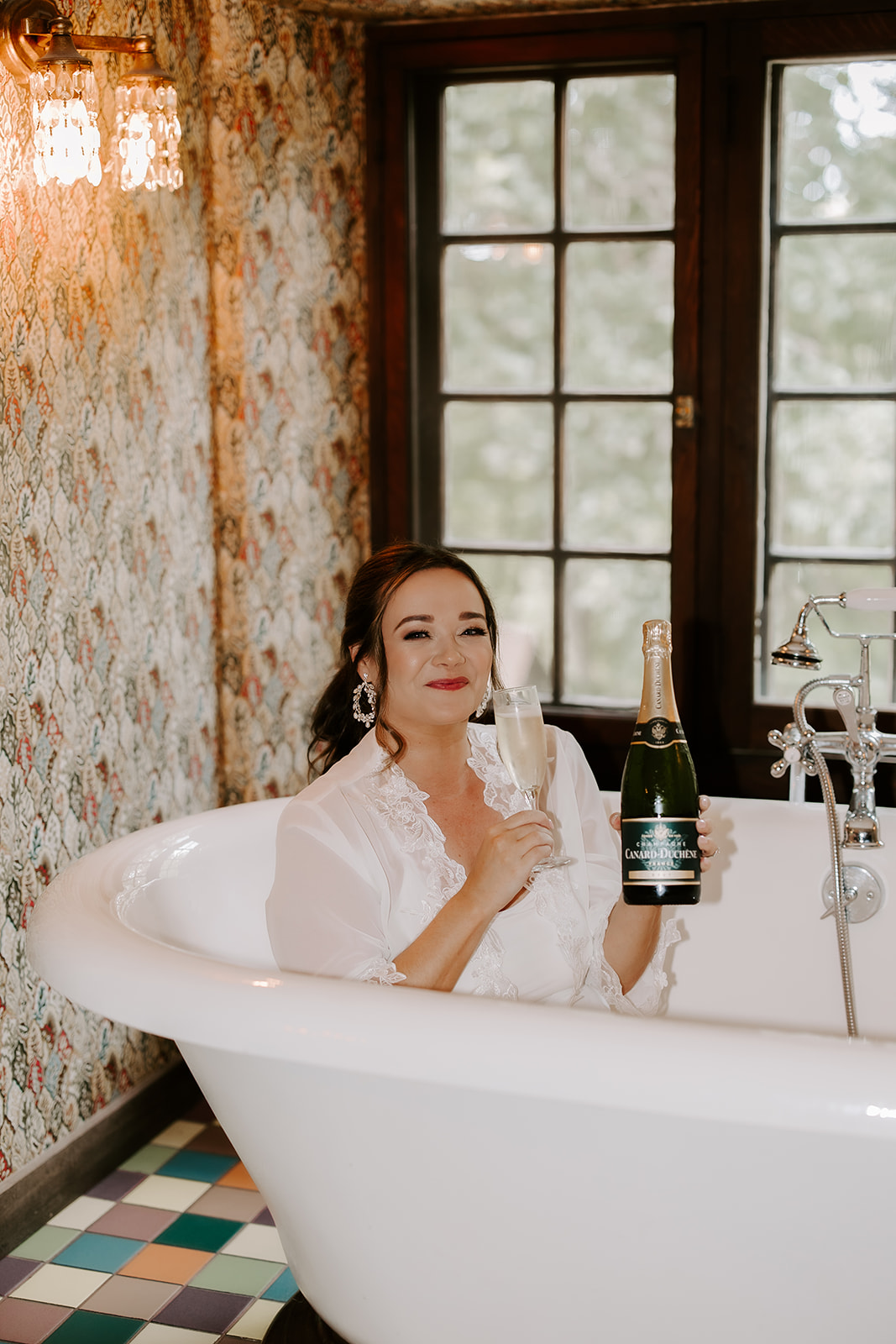bride celebrates with a glass of champagne in the bath tub 