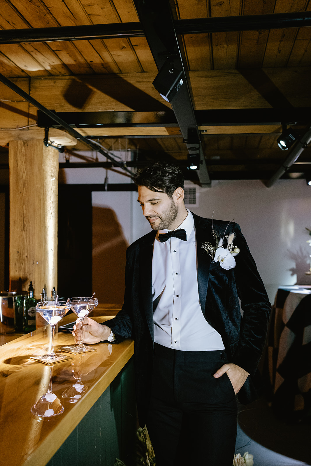 handsome groom poses at the bar with his martini glass