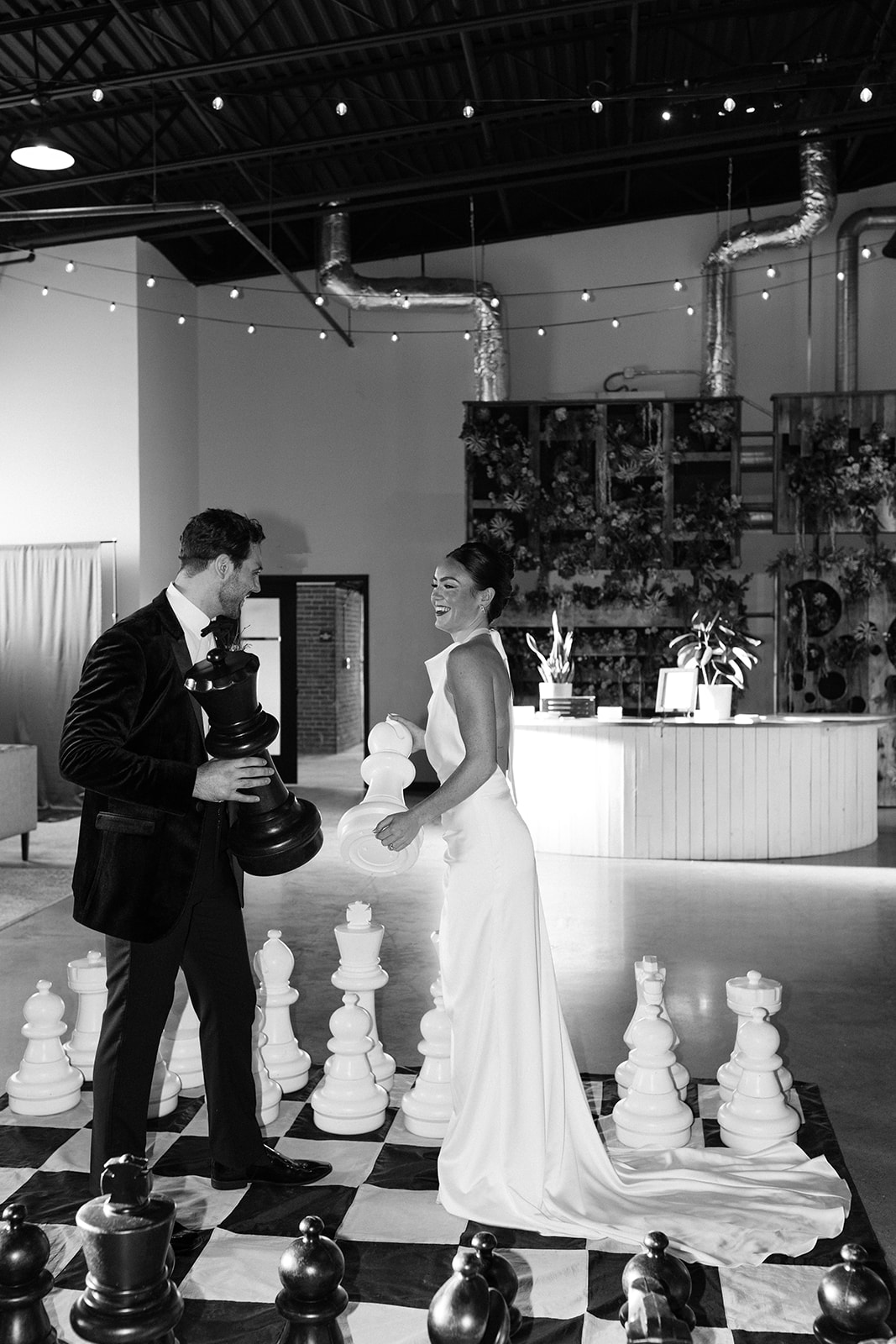 bride and groom play chess with the huge chess pieces