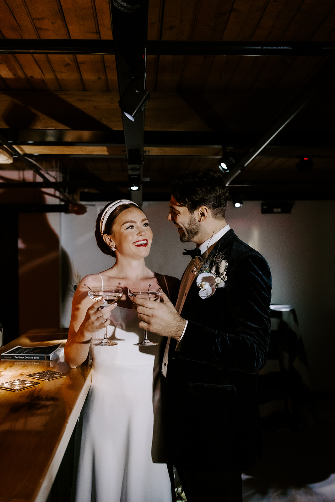 beautiful bride and groom poses at the bar with their martini glasses
