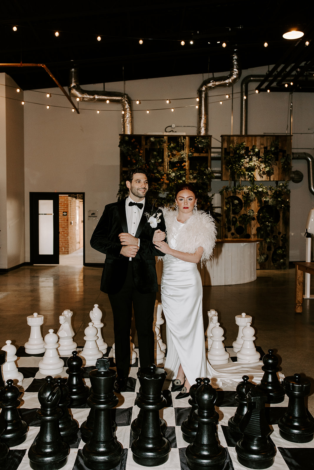 bride and groom pose with the giant chess set