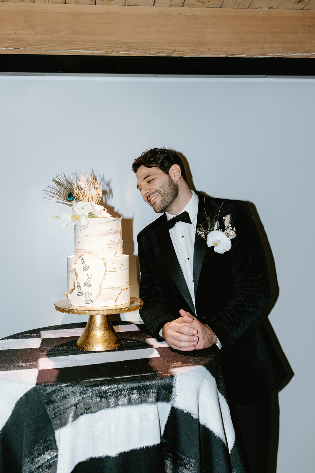 groom poses with the 2 tier wedding cake 