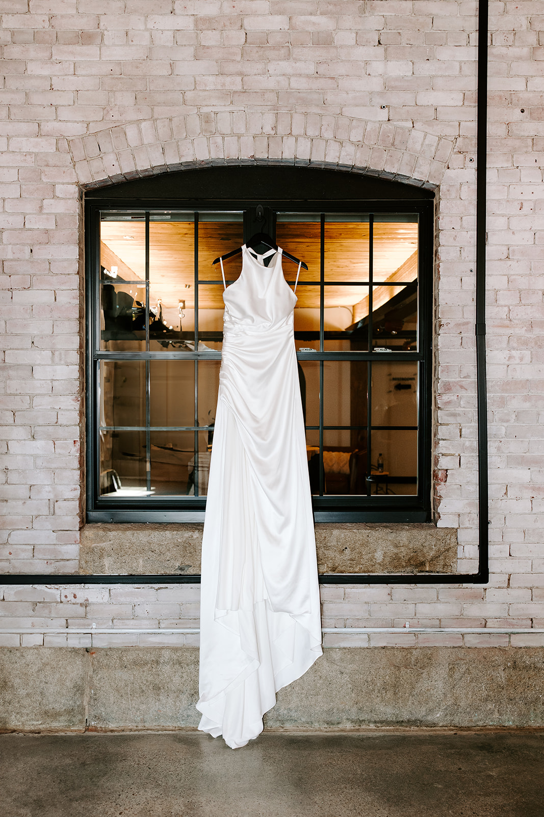 brides stunning wedding dress hangs at the dreamy factory wedding venue