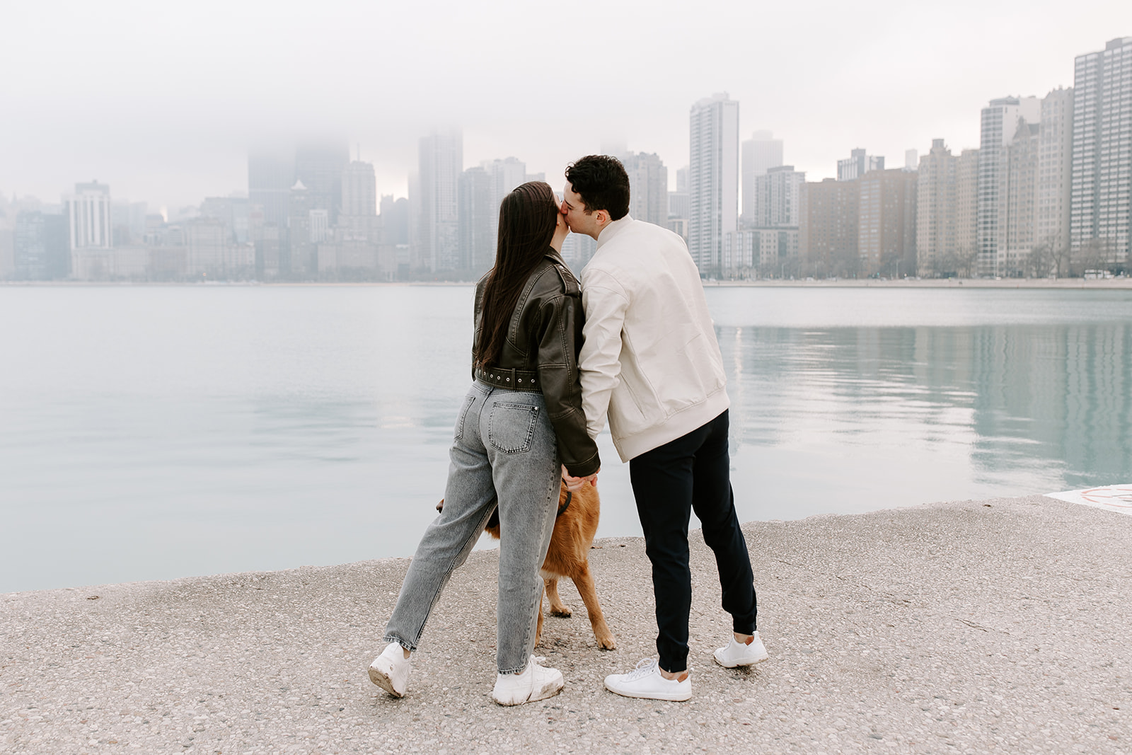 stunning couple pose with their dog and the skyline during their Chicago engagement photos 