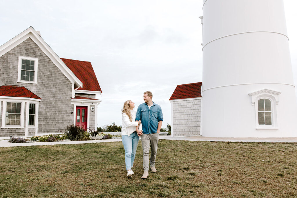 Wide-angle view of couple with lighthouse and ocean backdrop
