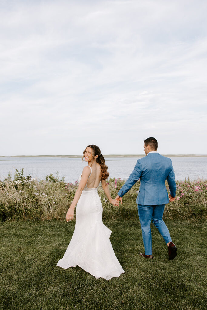 Bride and groom holding hands during golden hour at their Cape Cod backyard wedding in Orleans, MA