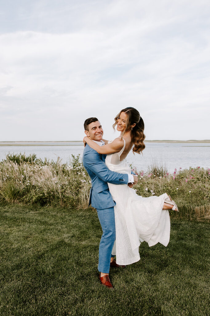 Newlyweds sharing a romantic sunset moment in a Cape Cod backyard, surrounded by glowing lanterns