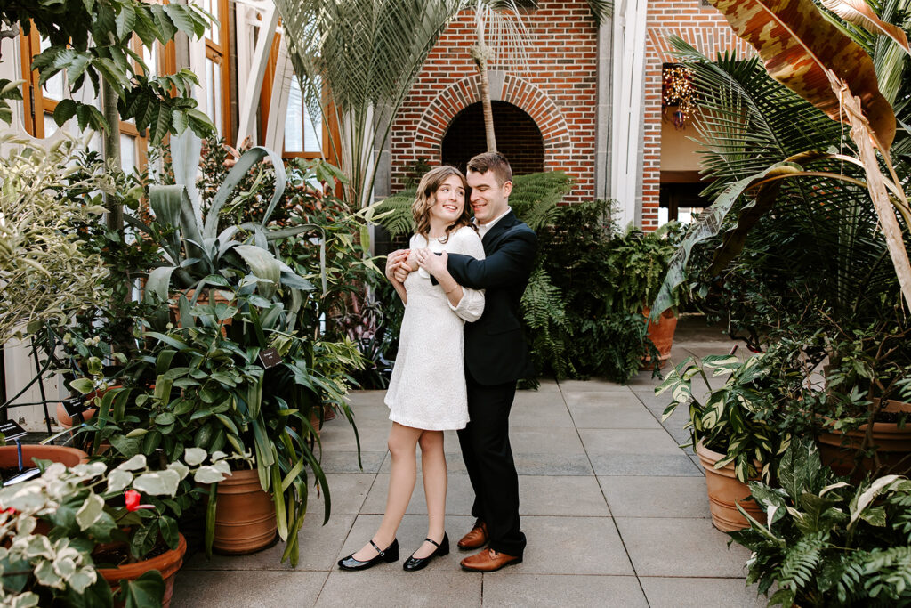 Couple sharing a quiet moment among potted plants and tropical leaves