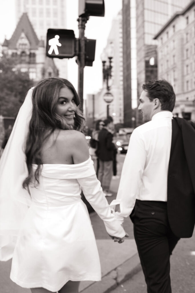 Candid moment of couple walking through Boston in stylish outfits
