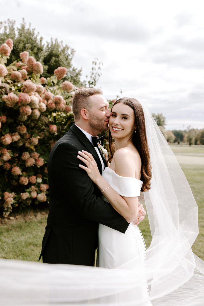 groom kissing bride with veil flowing