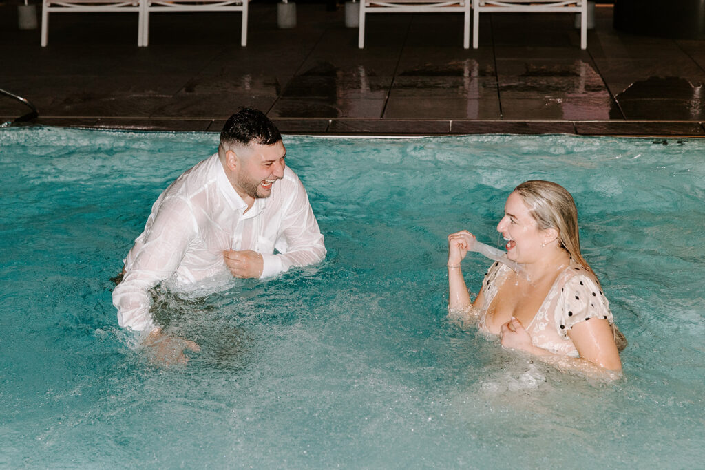 Playful splash in the hotel pool during an untraditional, fun engagement session.