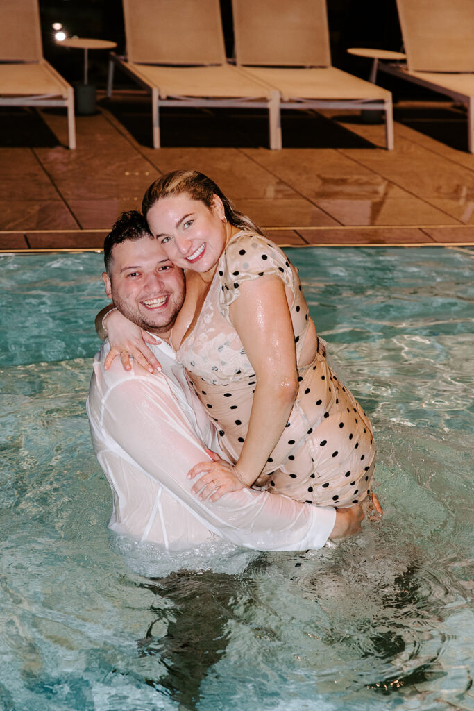 Groom lifting bride in the water, both soaking wet and smiling from ear to ear