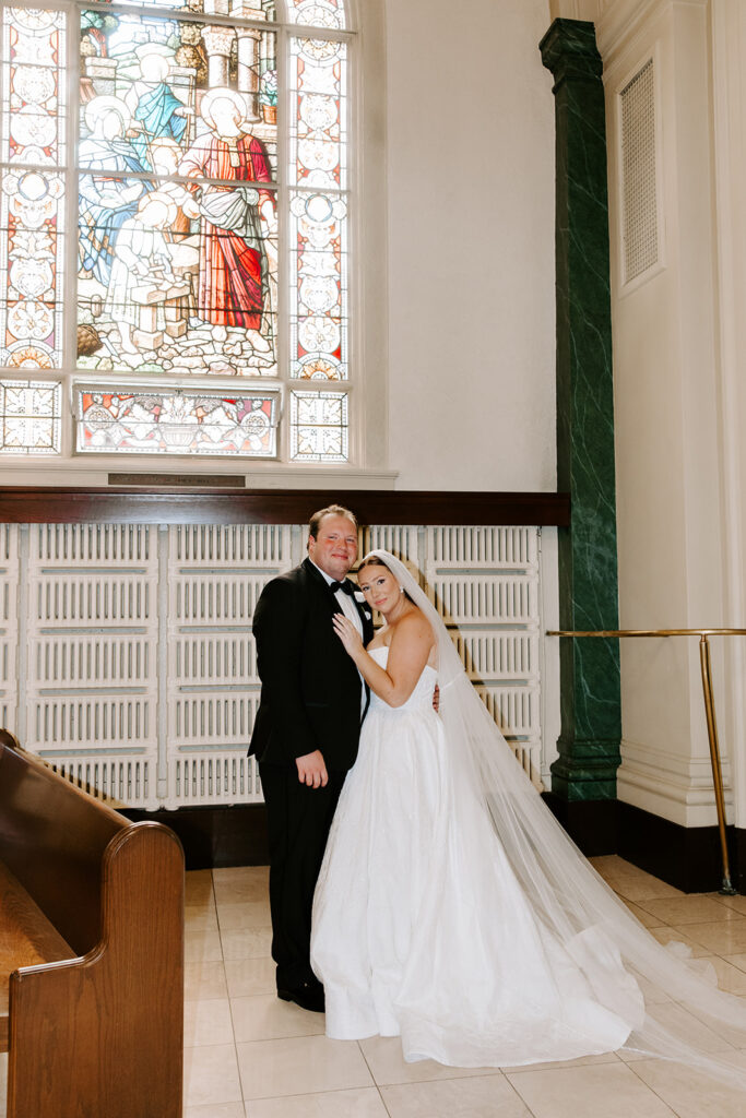 bride and groom posing in front of stained glass windows