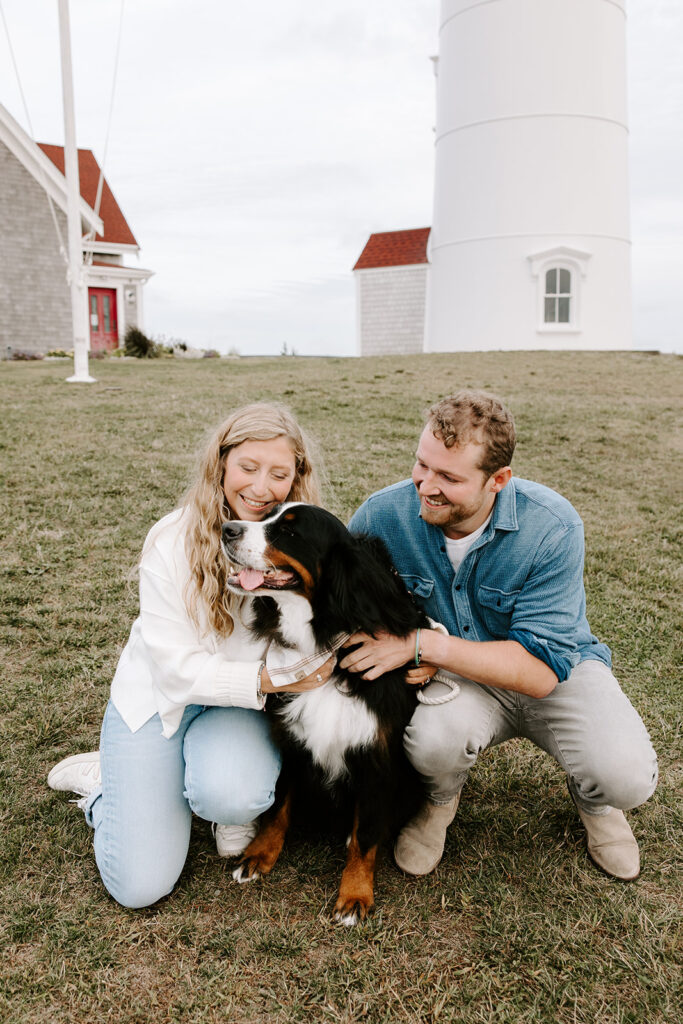 Engagement photo with dog sitting between the couple on the sand
