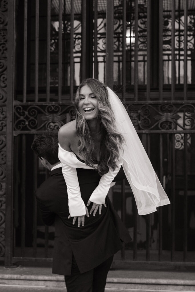 bride laughing as groom carries her