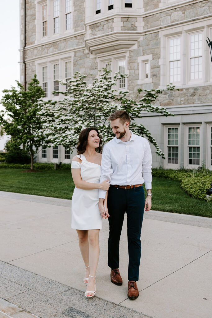 Couple in casual outfits smiling on Boston College lawn