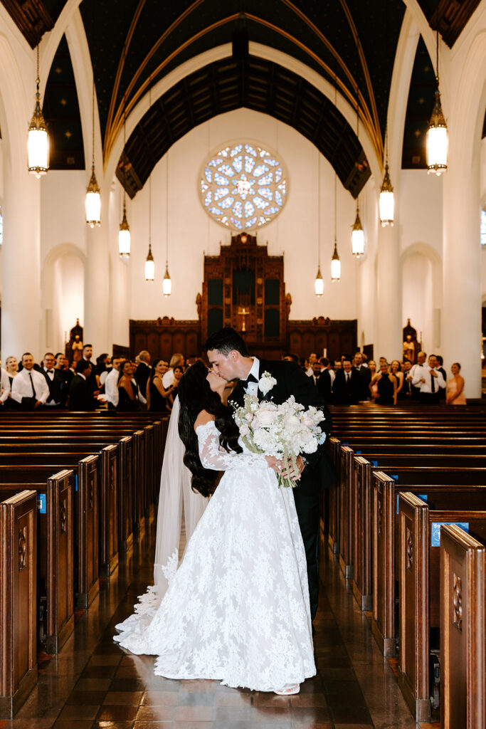 bride and groom kissing down aisle