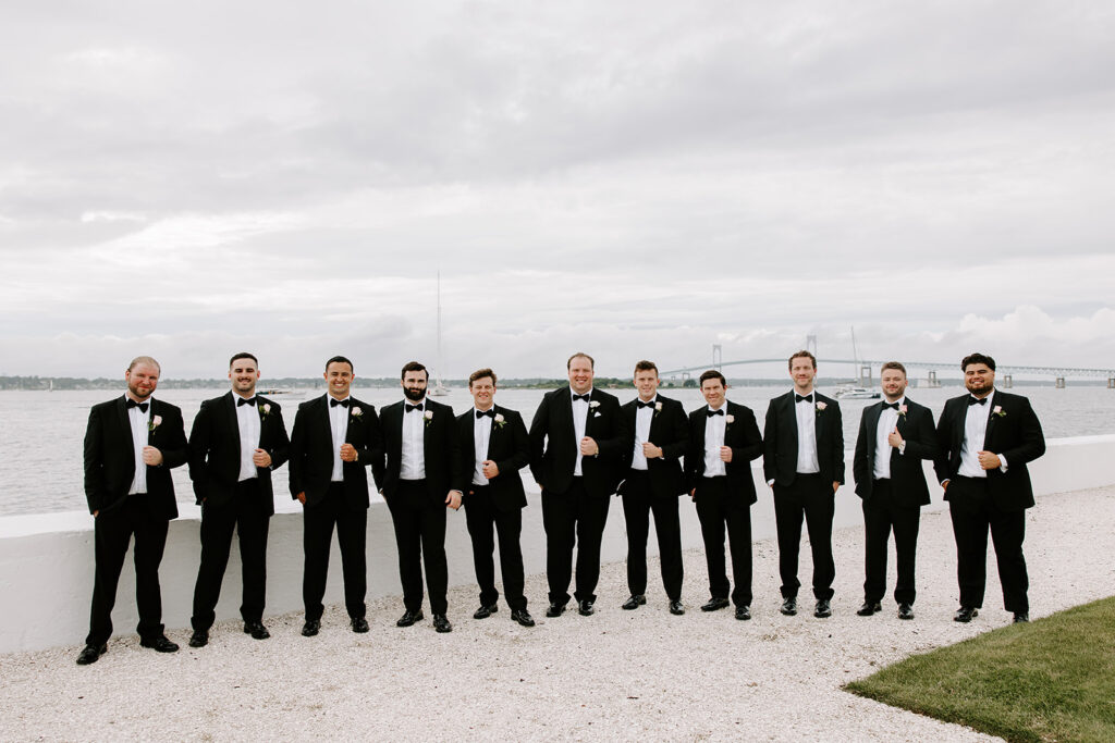 groomsmen posing in front of water