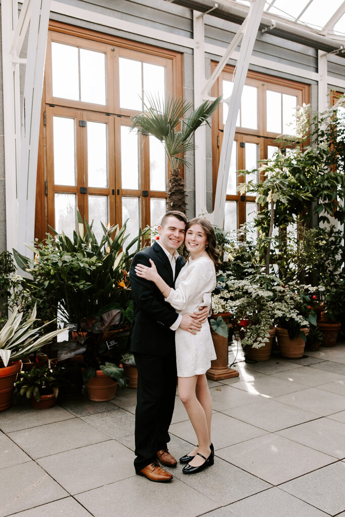 Intimate moment of couple under greenhouse archway filled with ferns and palms