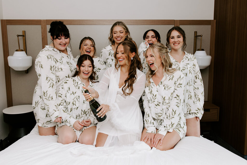 bridesmaids and bride popping champagne