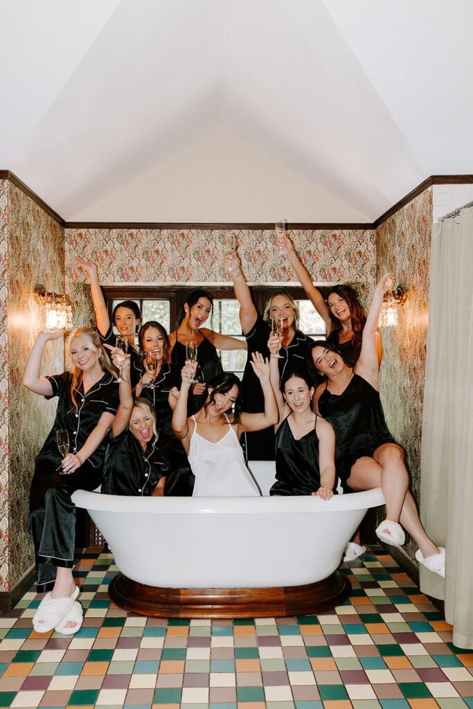 bride and bridesmaids in bathtub drinking champagne