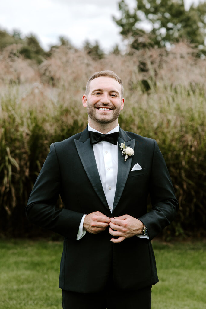 groom buttoning tux on the golf green