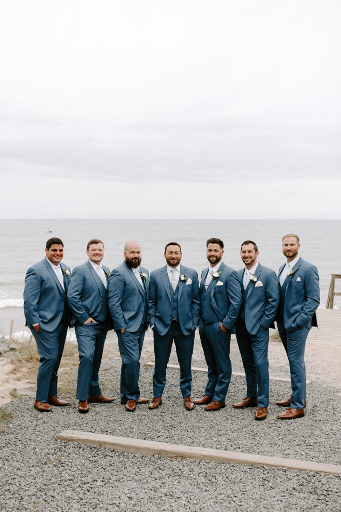 groomsmen standing along beach