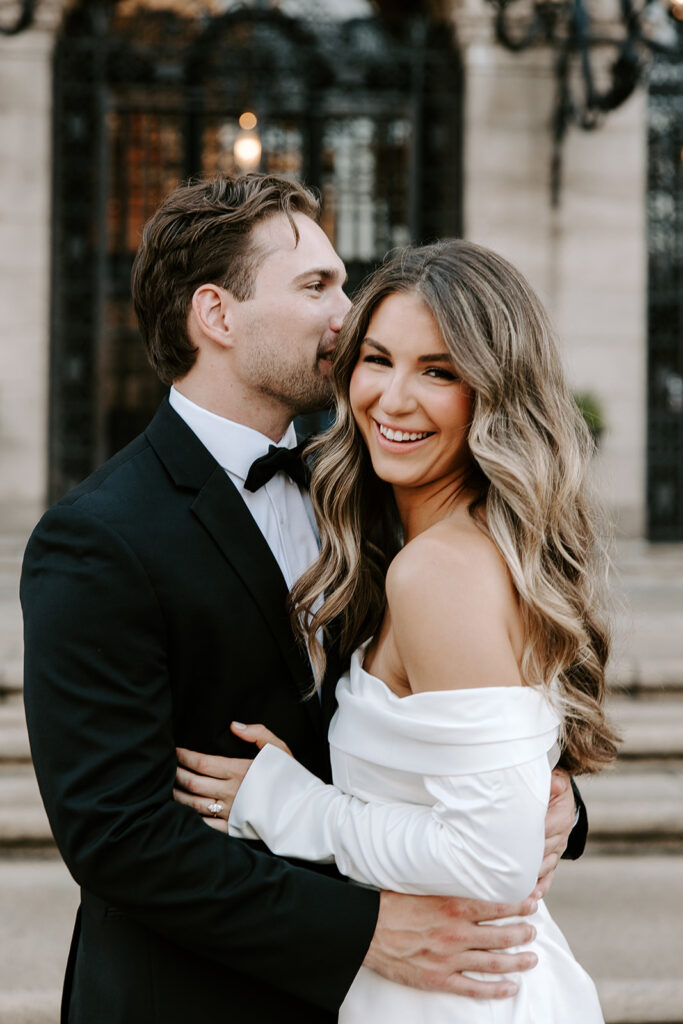 Couple leaning in for kiss under arched windows of Boston landmark