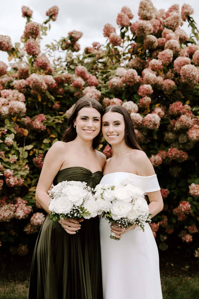 bride and maid of honor in front of pink flowers