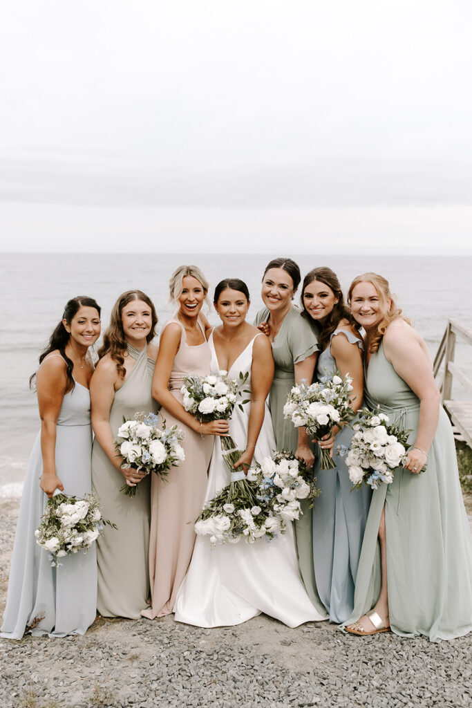 Bridesmaids in soft, neutral dresses holding floral bouquets
