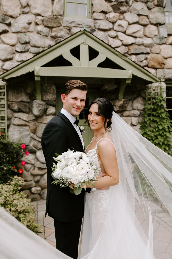 bride and groom with veil whisping in front of camera
