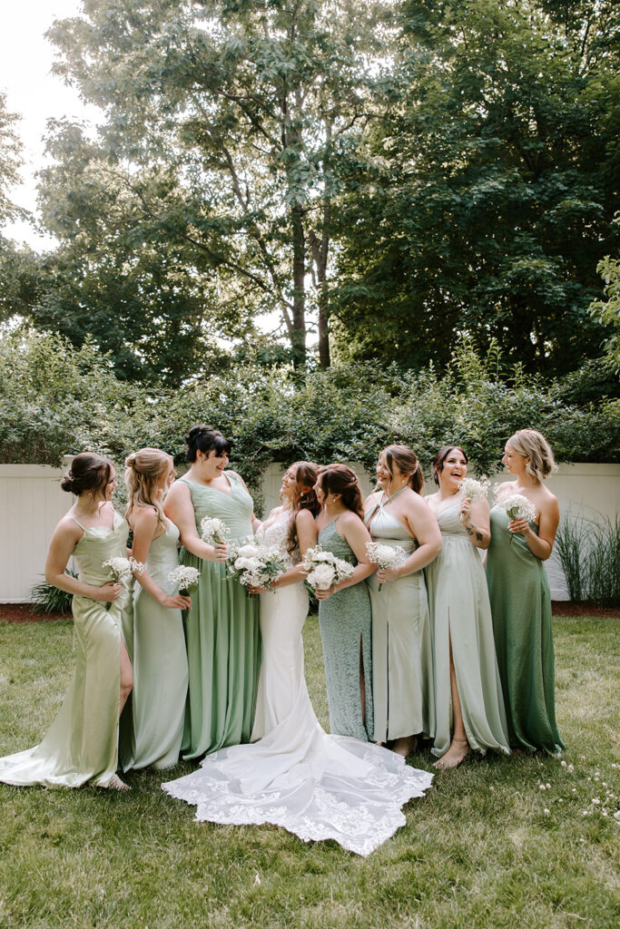 Bridesmaids in soft green dresses holding bouquets
